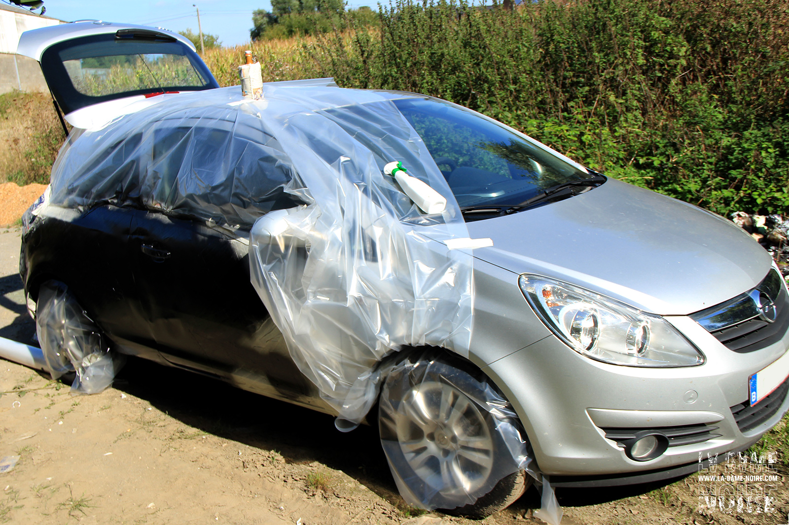 Flanc droit de l'opel corsa avec bâche de protection et peinture noire