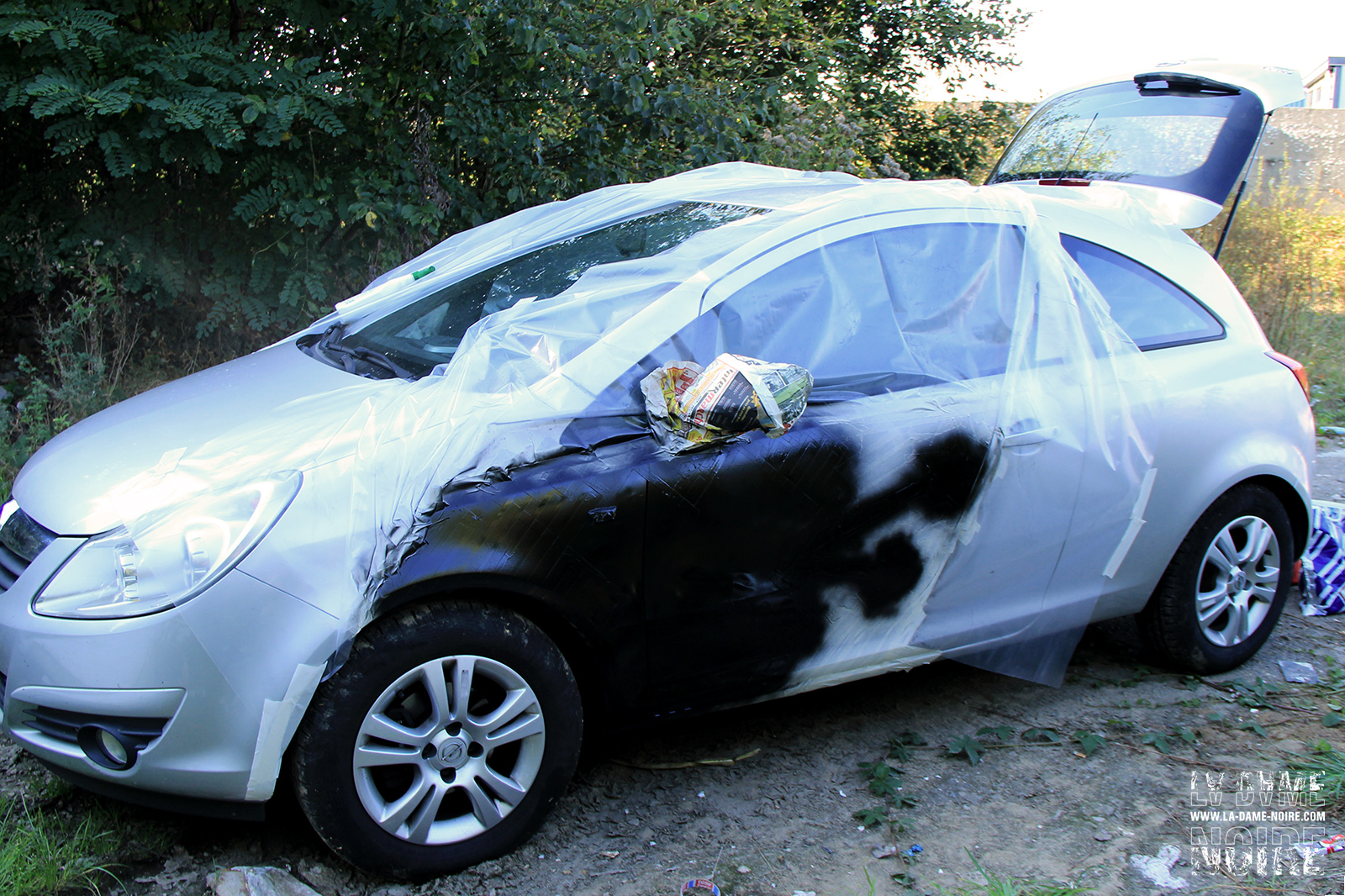 Flanc gauche de l'opel corsa avec bâche de protection et peinture noire